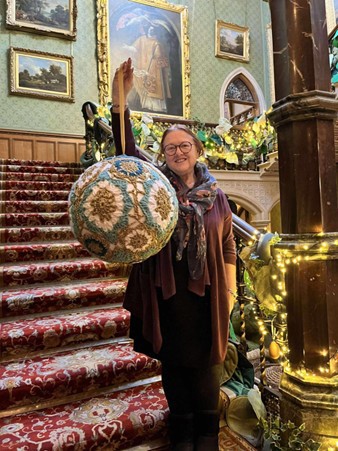 A women holding up a giant crocheted bauble.