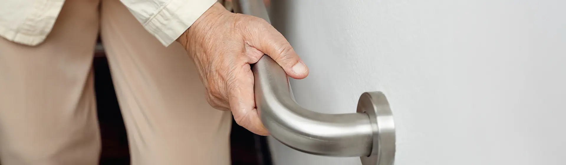senior person holing onto wall mounted mobility aid