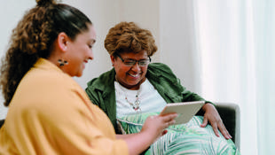 woman showing older woman laptop