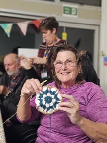 A women holding up a crochet granny square.