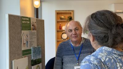 Tom Talking To A Colleague About His Art Project At The Customer Forum Event