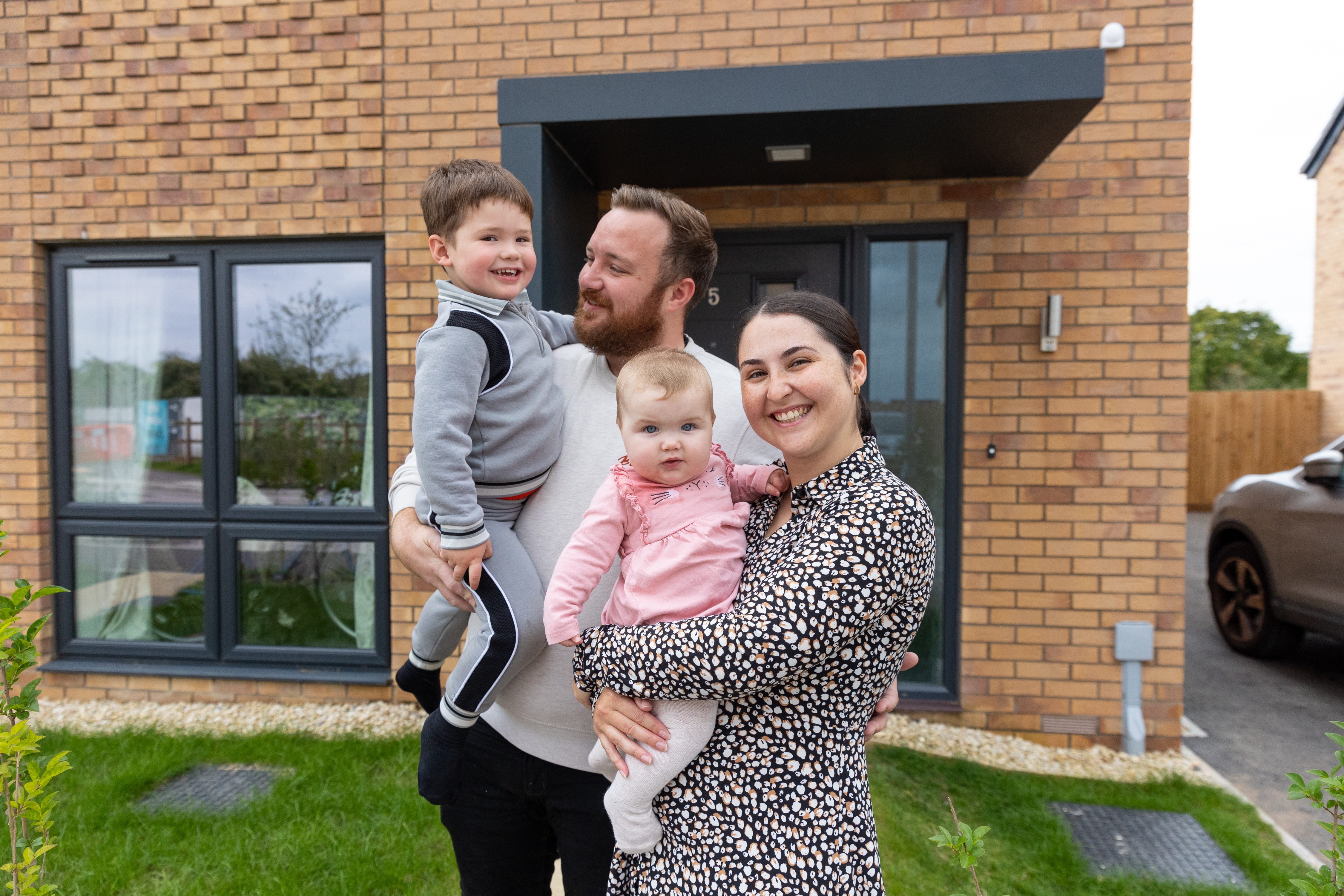 man woman and children in front of home