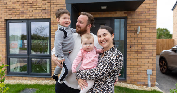 man woman and children in front of home